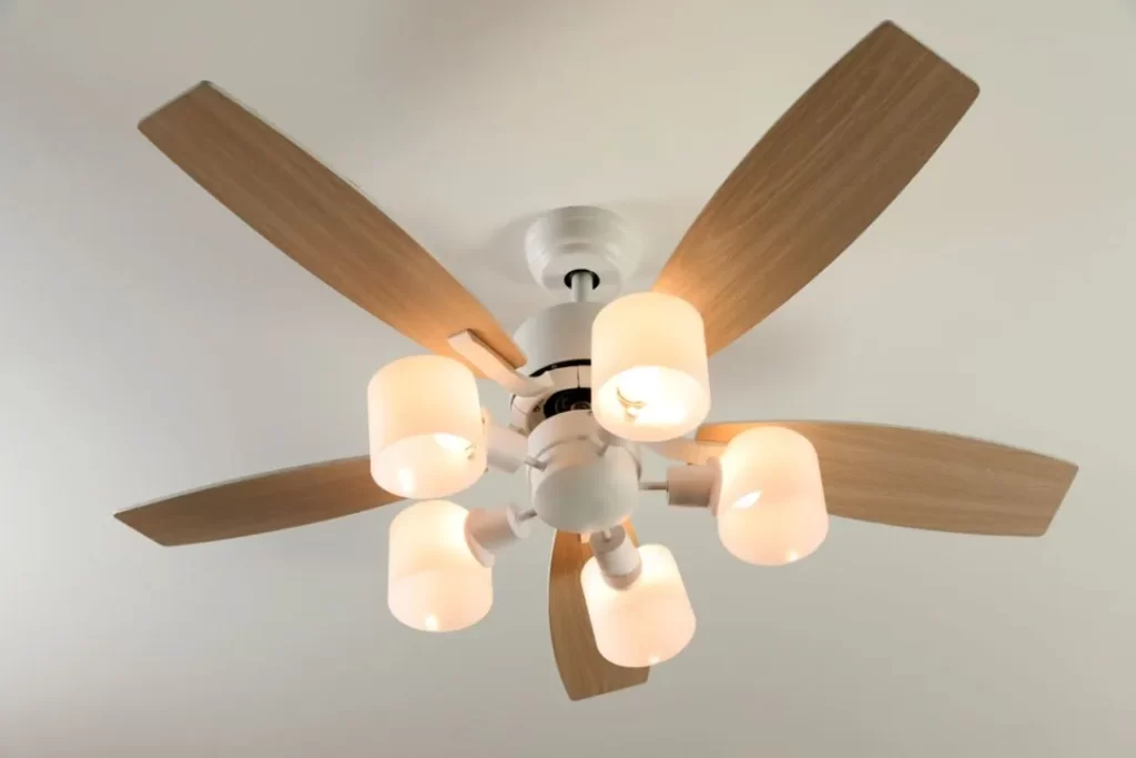 Modern ceiling fan with wooden blades and five illuminated light fixtures, professionally installed on the Sunshine Coast.