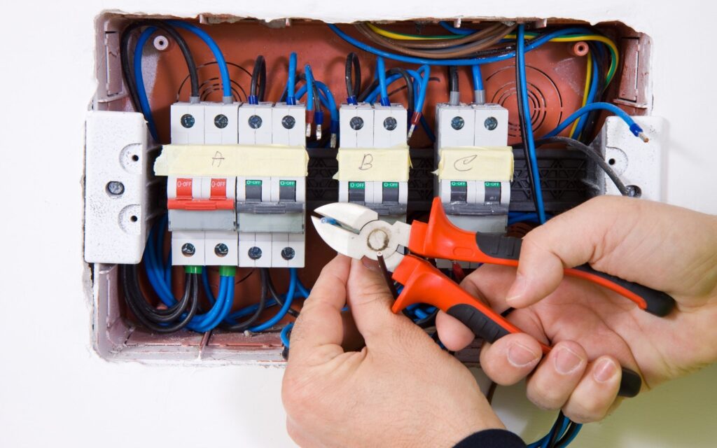 Electrician from Sunshine Coast Electrician using wire cutters to work on switchboard wiring during installation in Maroochydore