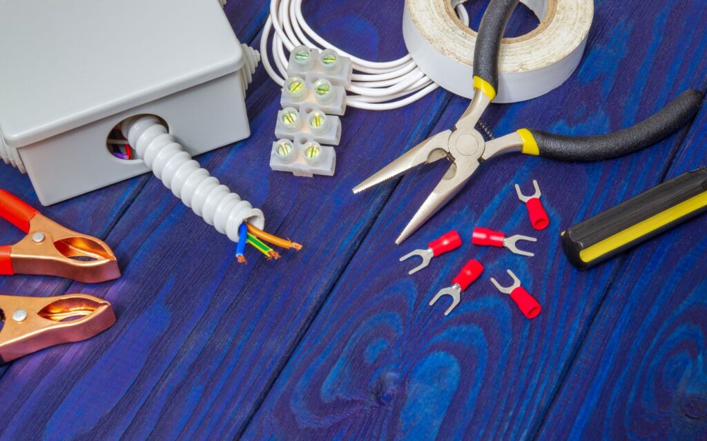 Electrical tools and wiring accessories laid out on blue wooden surface for Sunshine Coast Electrician services