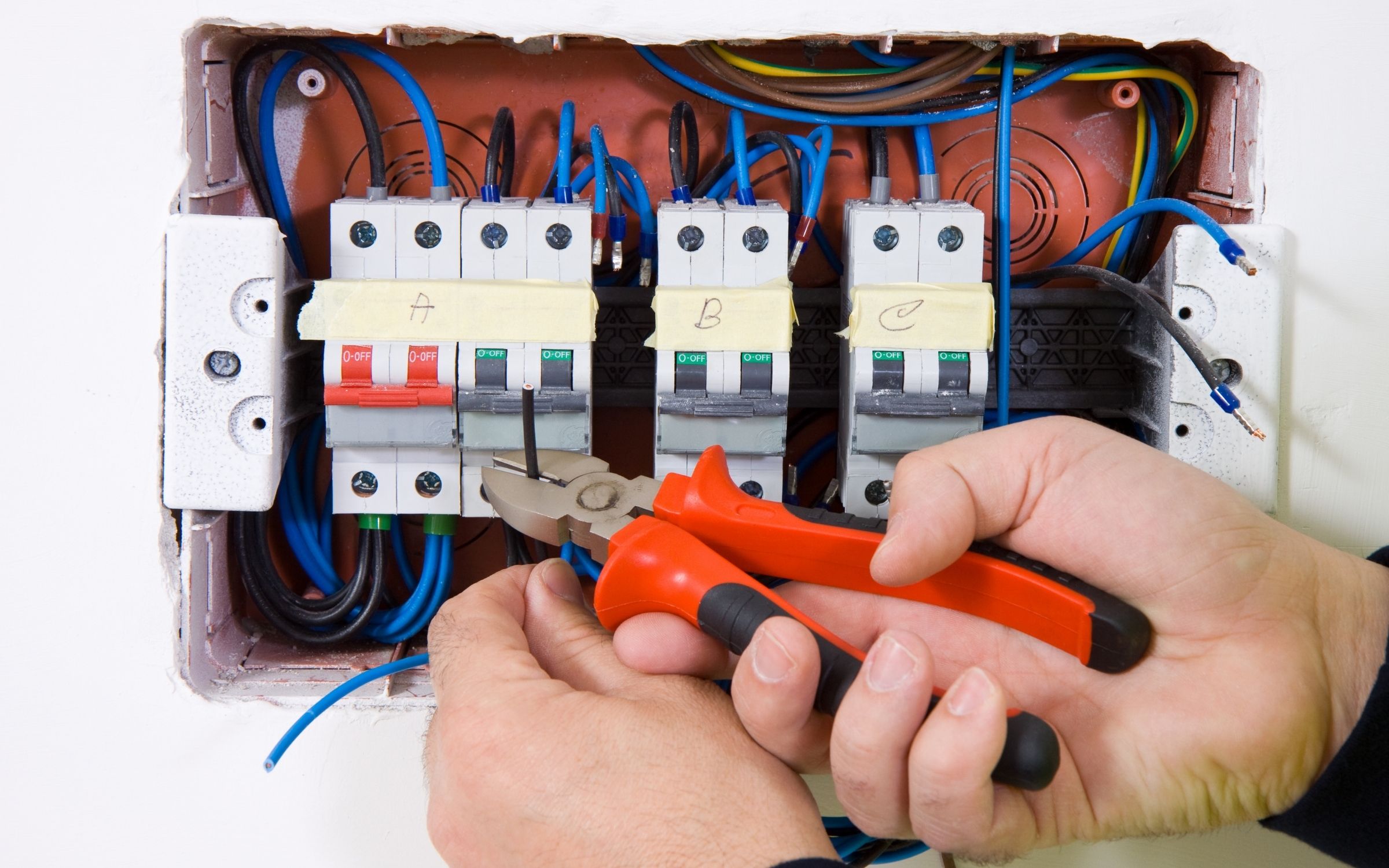 How 3-Phase Power Installations Can Benefit Your Business 2 Electrician from Sunshine Coast Electrician upgrading electrical switchboard wiring with red-handled wire cutters