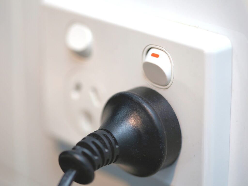 Professional power point installation by Sunshine Coast Electrician showing a black plug securely inserted into a white electrical socket with switch in on position, demonstrating safe electrical installations and power point upgrades for modern homes.