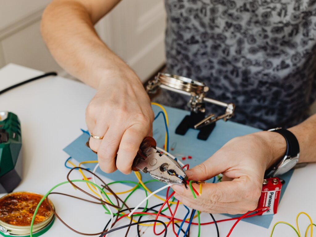 Person attempting DIY electrical work using extension cords, highlighting unsafe and illegal practices in Queensland